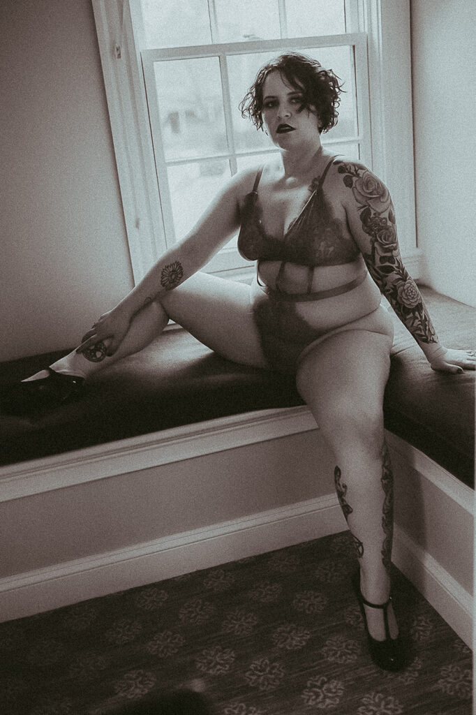 A woman sits with legs open on a bench in a window in lingerie after getting Missoula laser hair removal