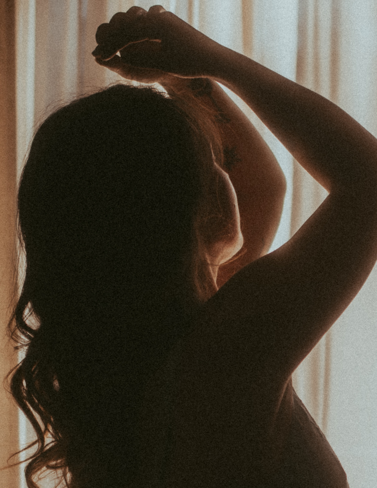 A silhouette of a woman with hands above her head in a window