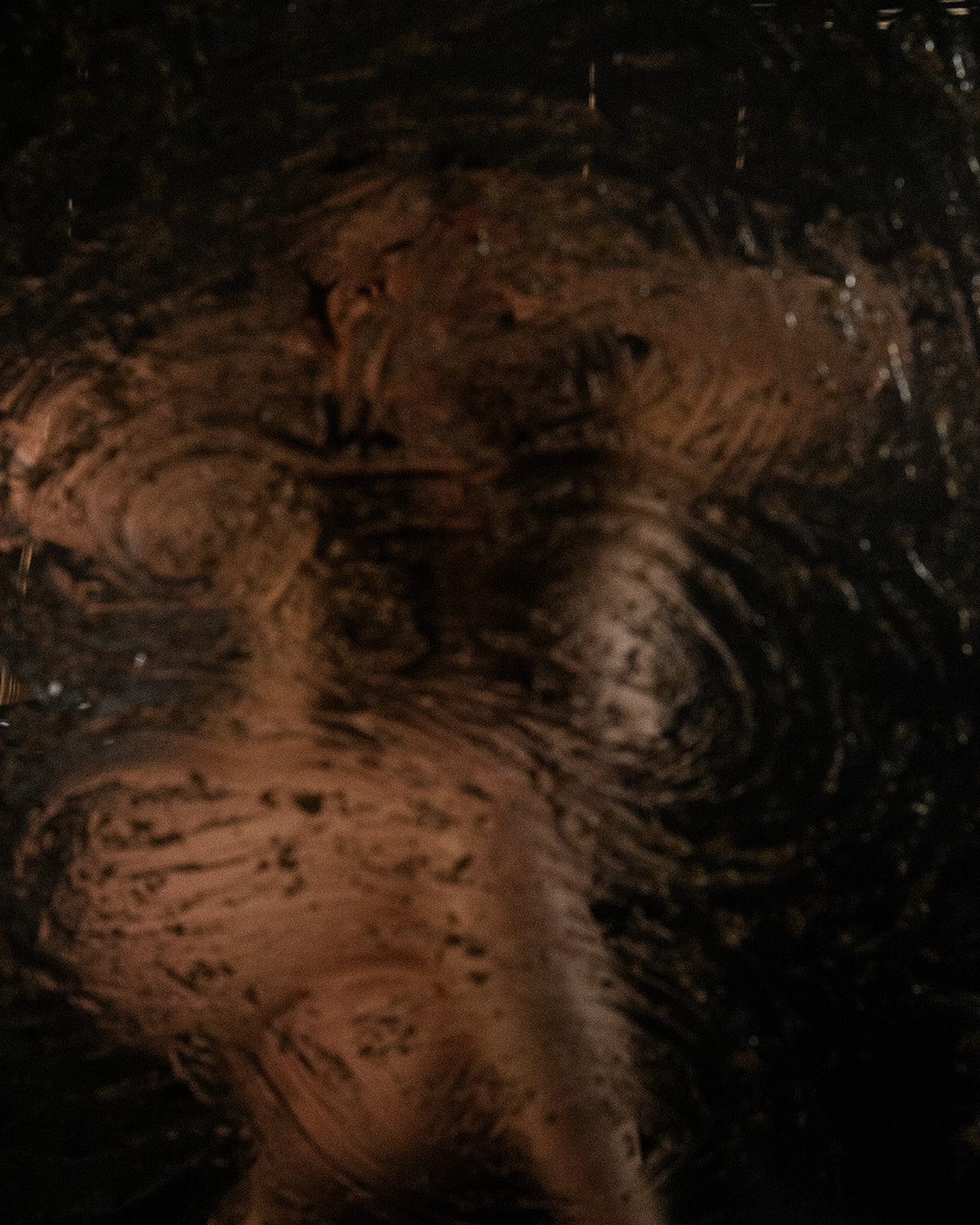 An image through a wet glass of a woman laying with legs crossed after tanning in Kalispell, MT
