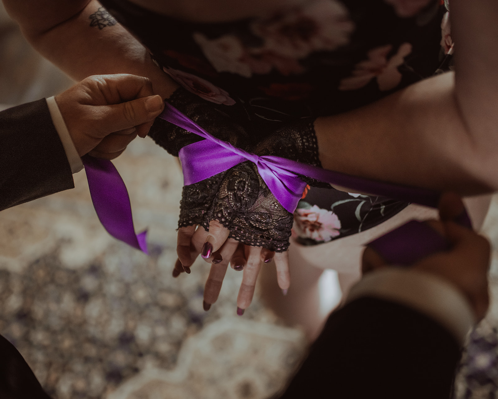 A man ties his wife's hands behind her back with purple ribbon in a bedroom after visiting beauty salons in Butte, MT