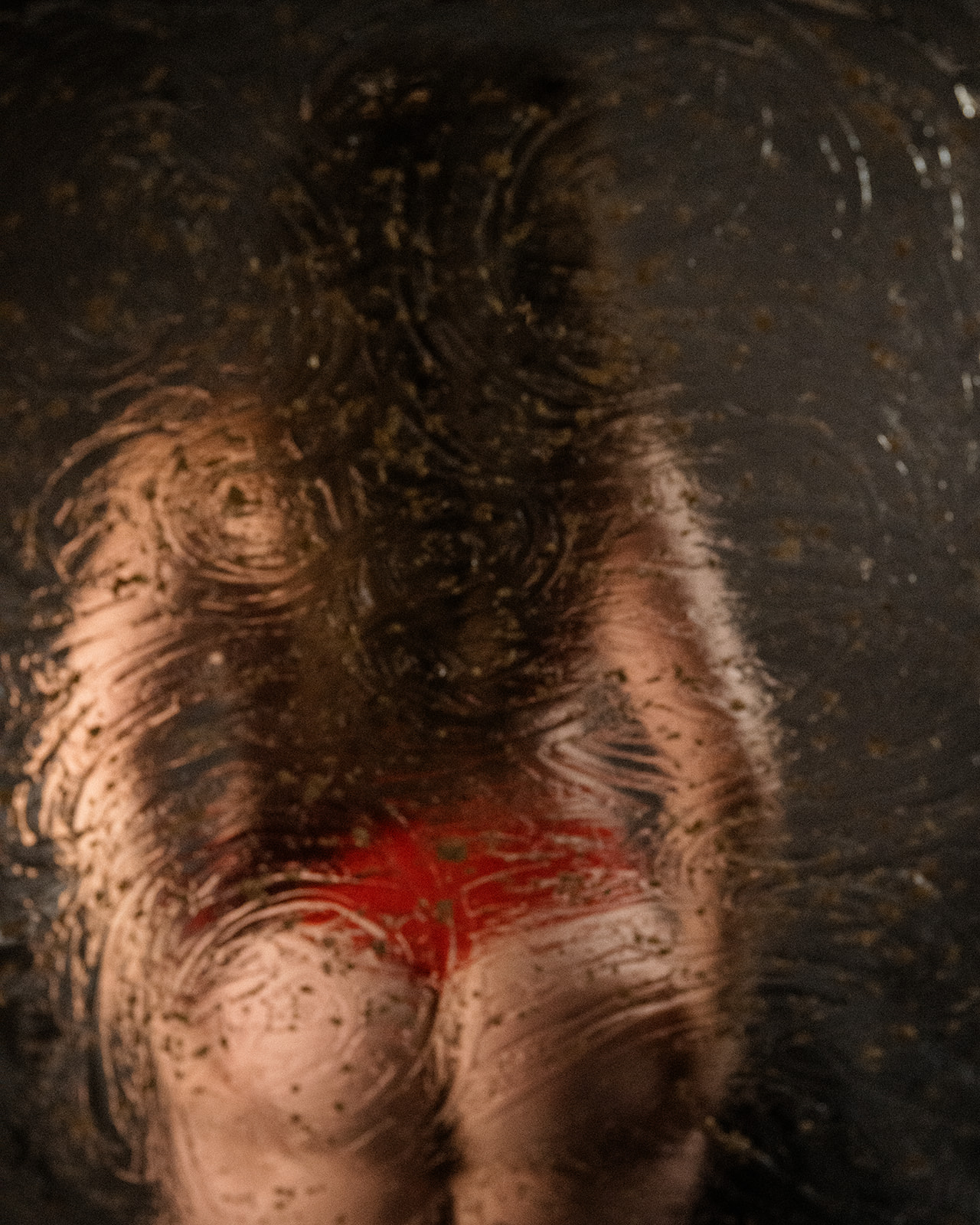 A look through textured glass to a woman in red lingerie after a Brazilian Wax in Missoula