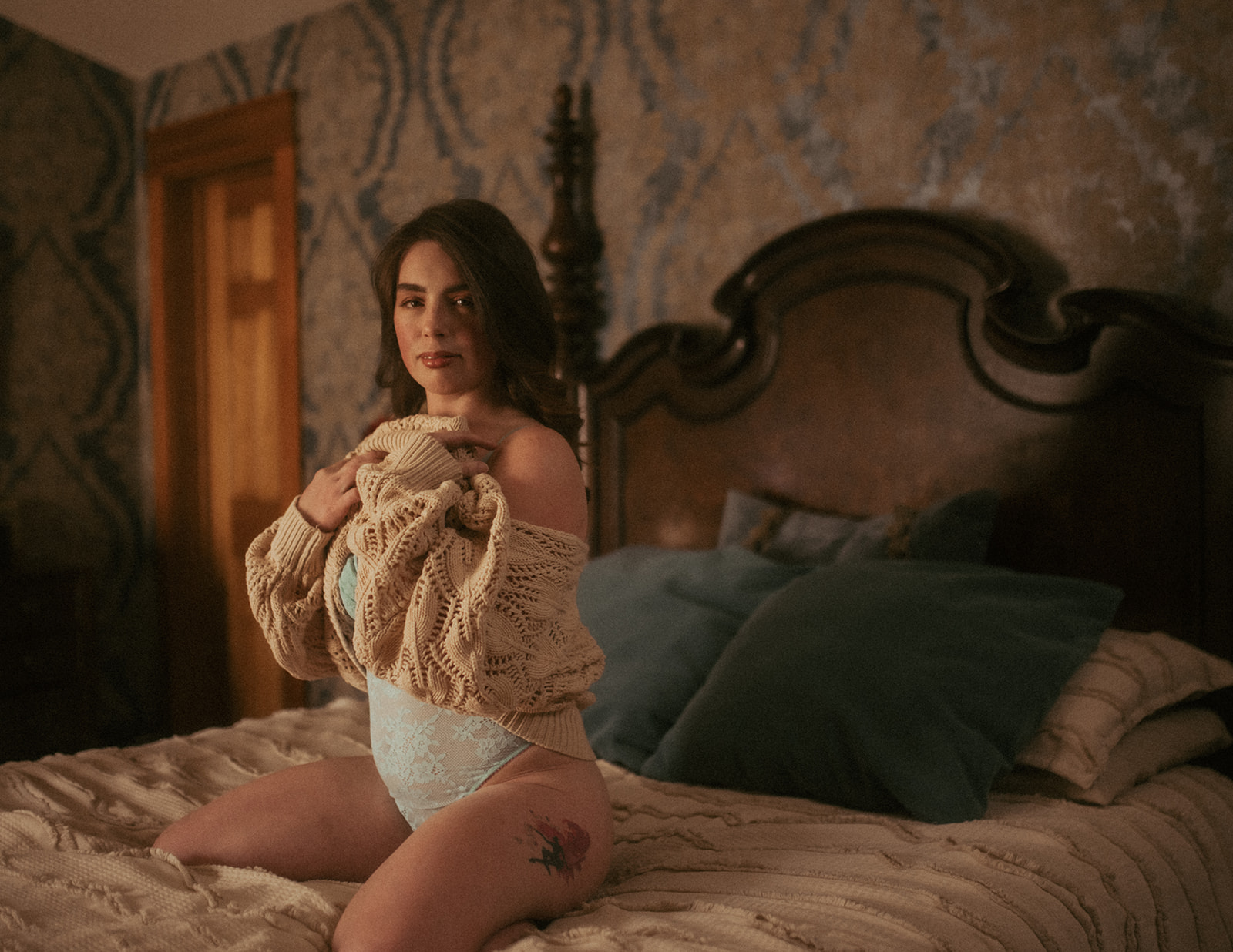 A woman pulls off a sweater to reveal blue lingerie while kneeling on a bed after enjoying day spas in Missoula