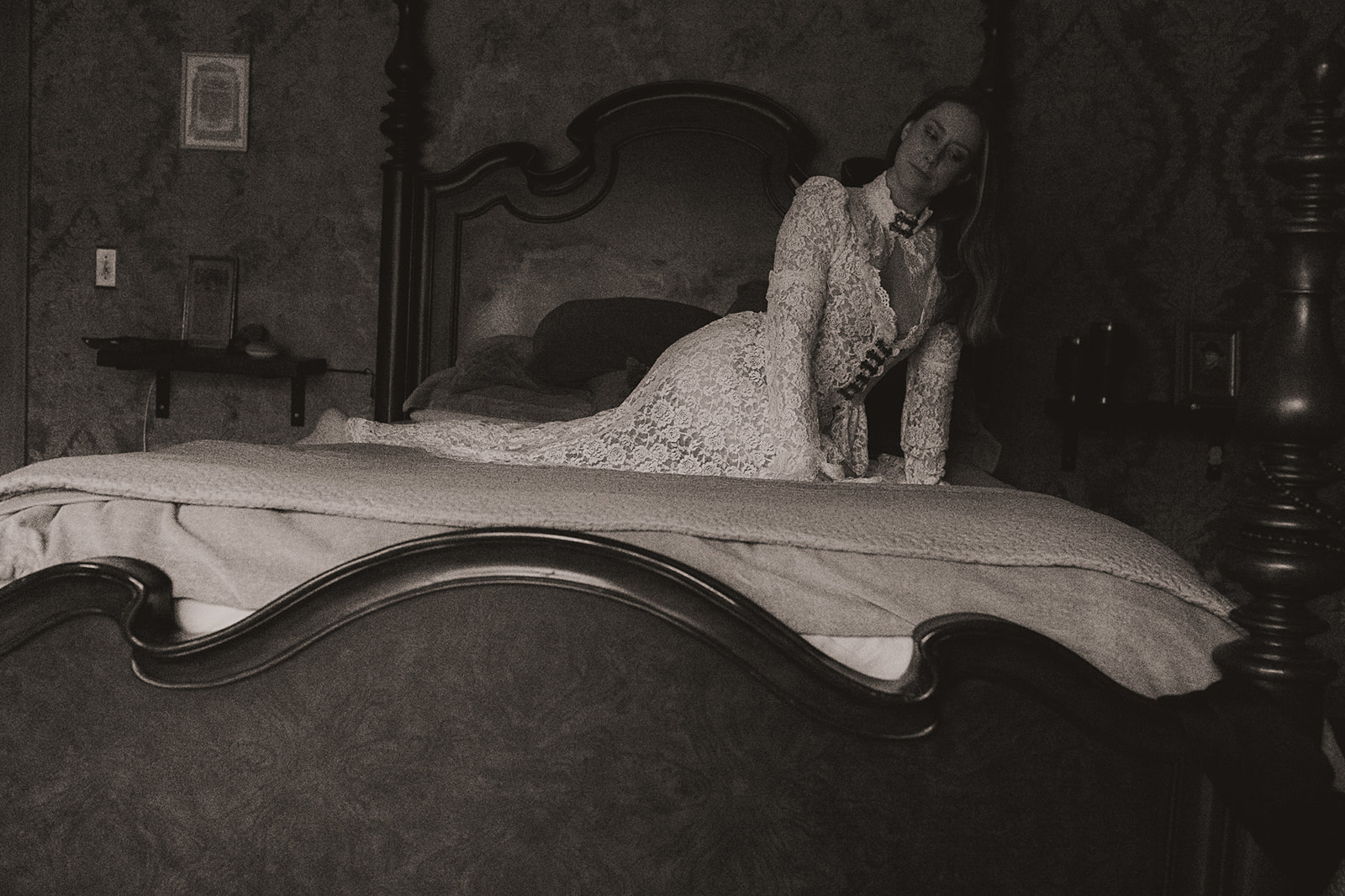 A black and white image of a woman kneeling across a bed in a vintage white lace gown after visiting Med Spas in Kalispell