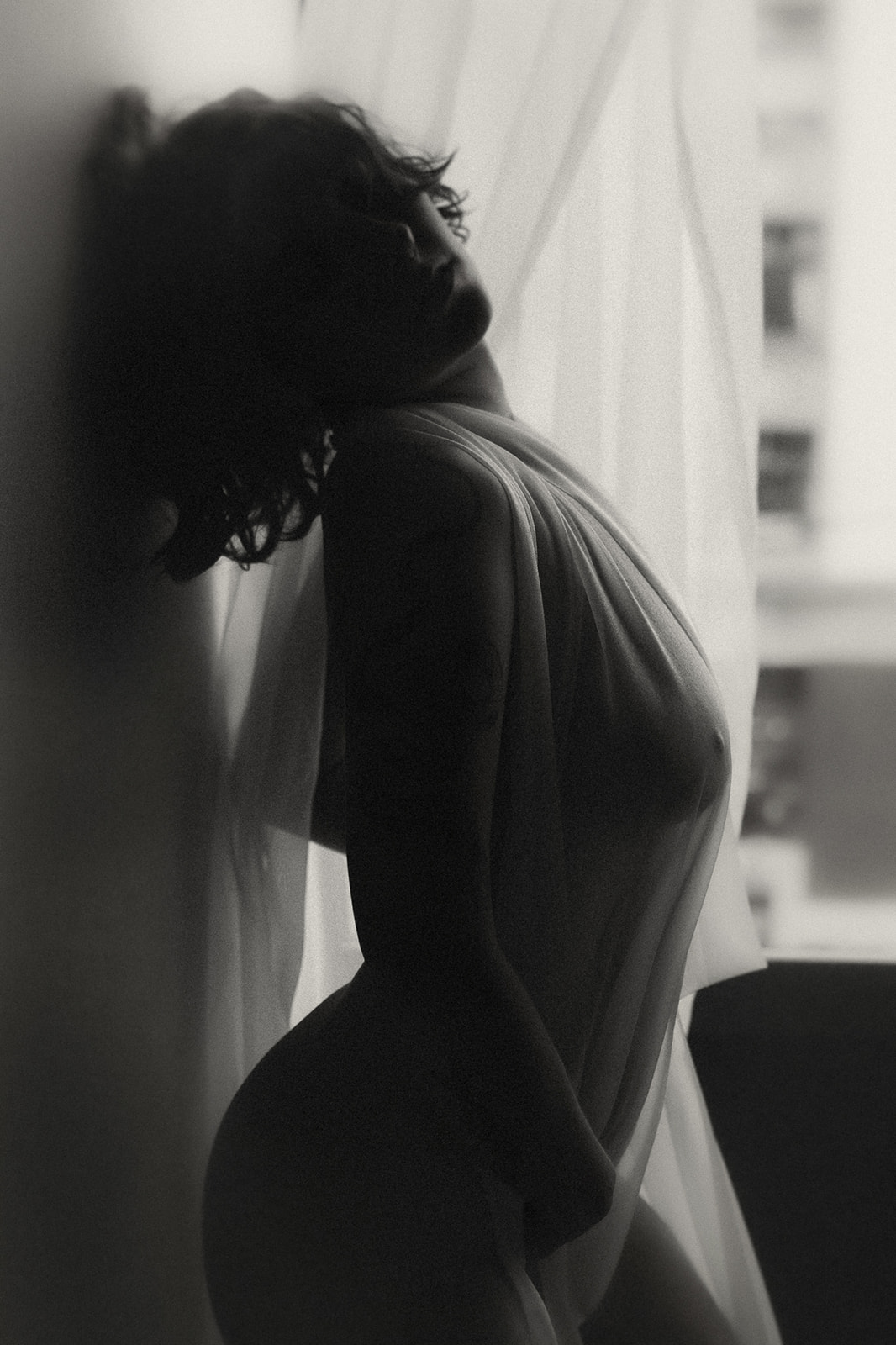 Silhouette of a woman covered in a sheer sheet leaning against a wall after visiting Medical Spas in Missoula