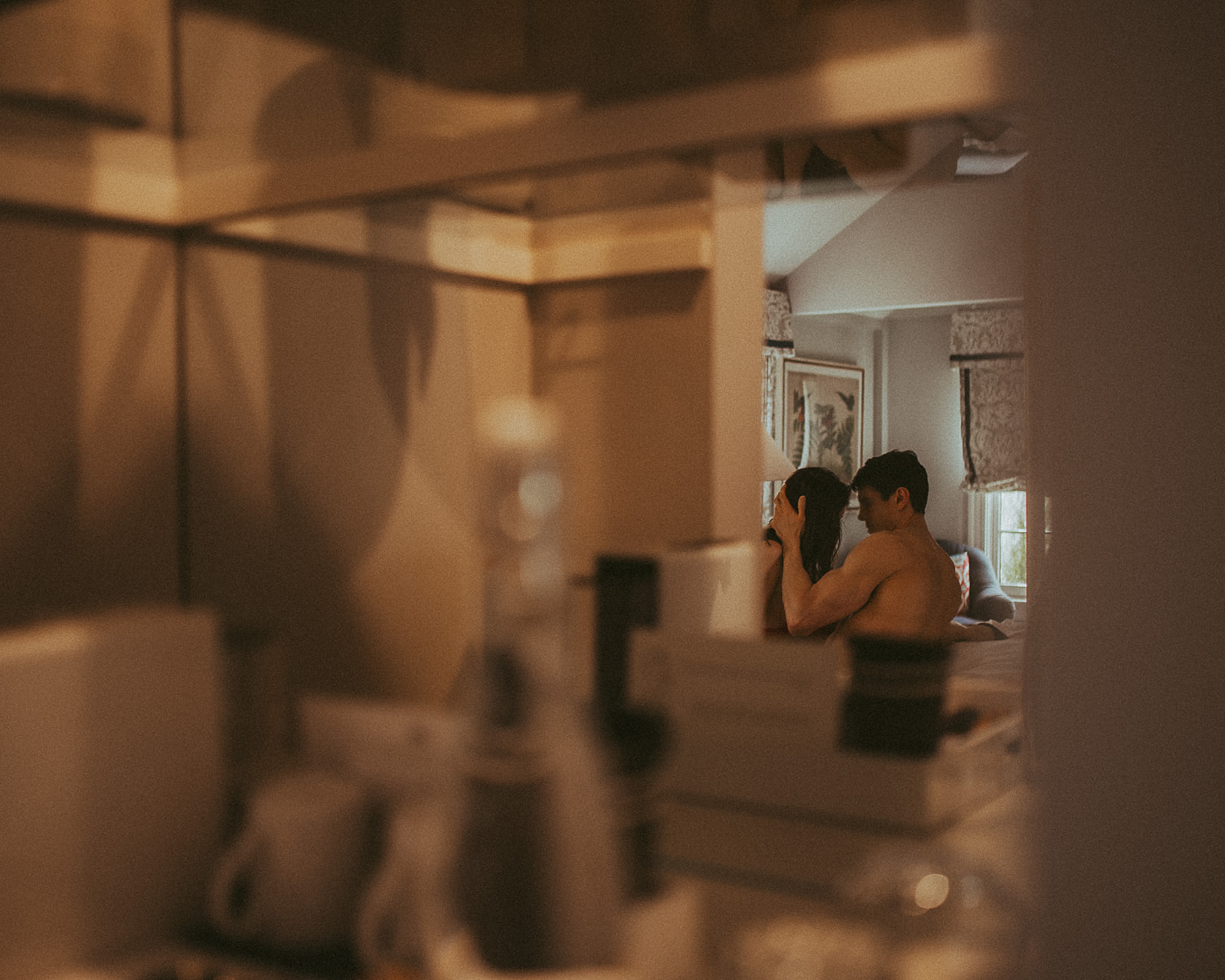 A peek through a doorway at a couple leaning in for a kiss on a bed after enjoying romantic things to do in Missoula, MT