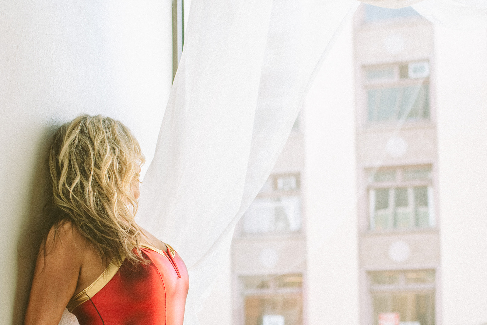 A woman in a wonder woman costume leans against a window sill after some barre fitness in Kalispell