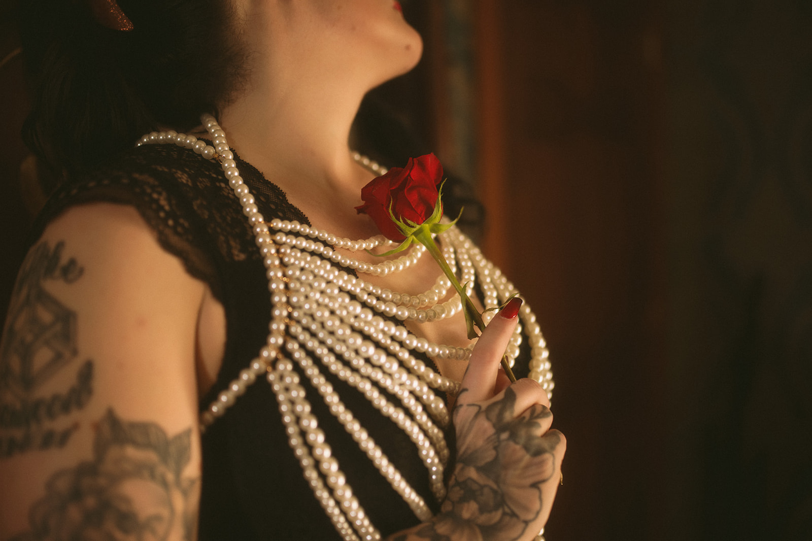 Details of a woman holding a rose against her chest covered in pearls after some pole fitness in Kalispell