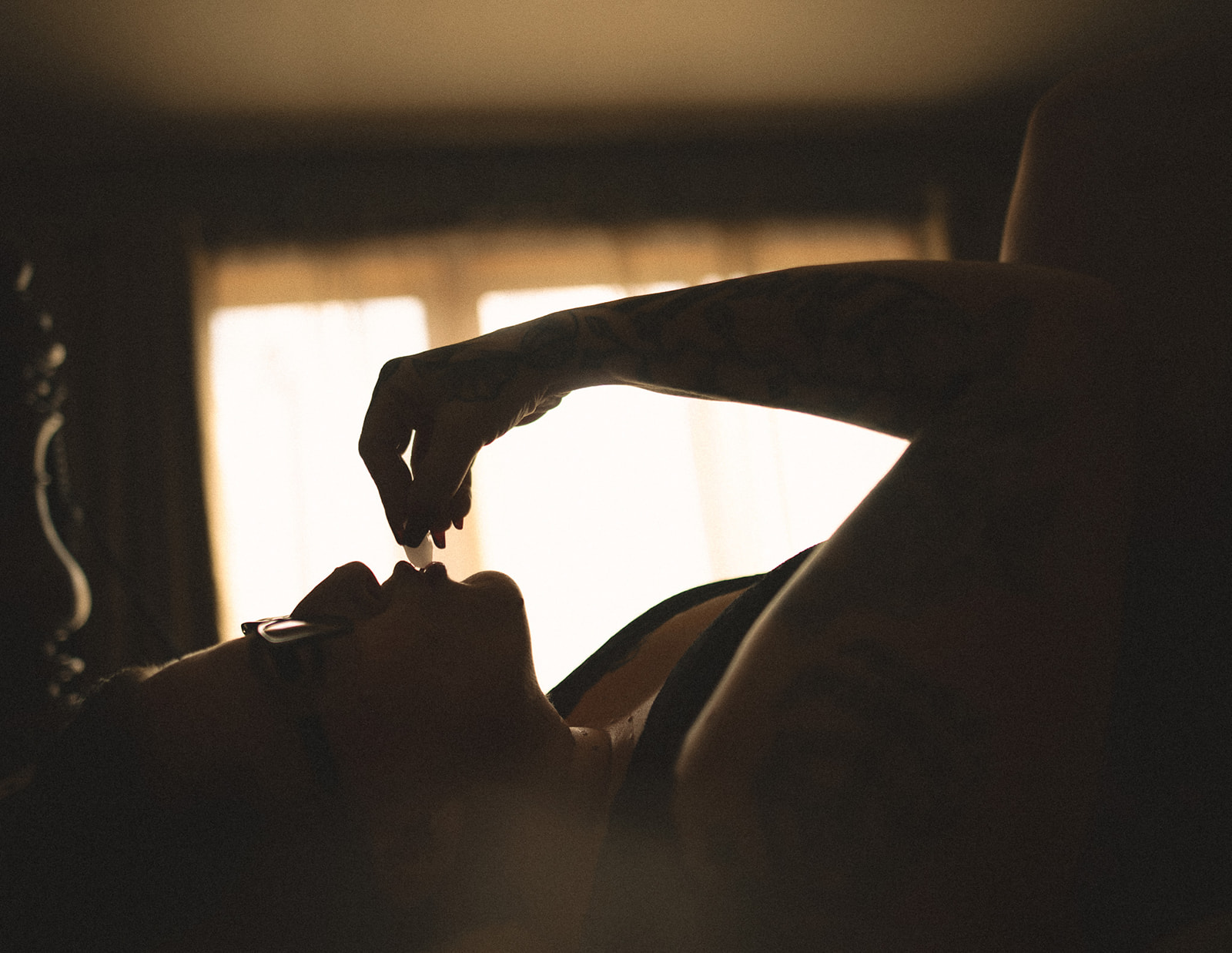 Silhouuette of a woman touching laying on her back touching an ice cube to her lips after finding lash extensions in Kalispell